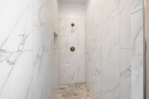 Full bath with a marble finish shower