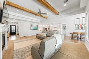 Living area featuring ceiling fan, beam ceiling, a fireplace, recessed lighting, and light wood-style flooring