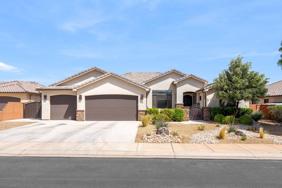 Ranch-style house featuring a gate, a garage, stone siding, and stucco siding