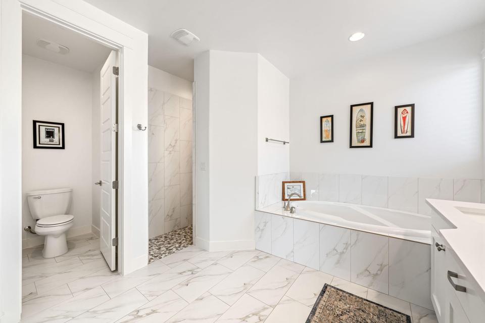 Bathroom featuring a bath, a marble finish shower, vanity, and light marble finish flooring