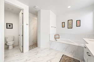 Bathroom featuring a bath, a marble finish shower, vanity, and light marble finish flooring