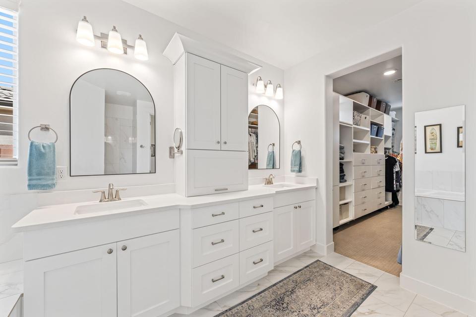 Full bathroom with double vanity, a spacious closet, and light marble finish flooring