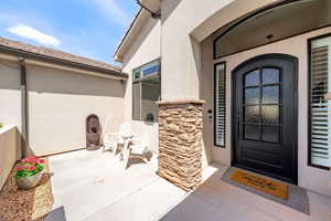 View of exterior entry with stucco siding and stone siding
