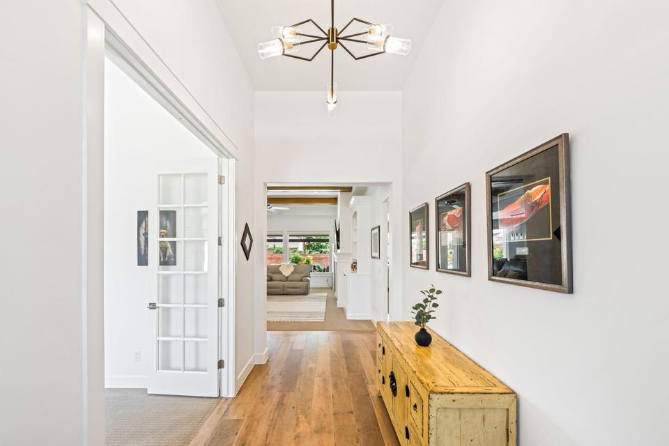 Hall with light wood-style flooring and suspended lighting