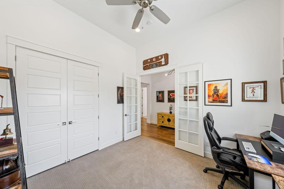 Office space featuring french doors, light carpet, a ceiling fan, and a high ceiling