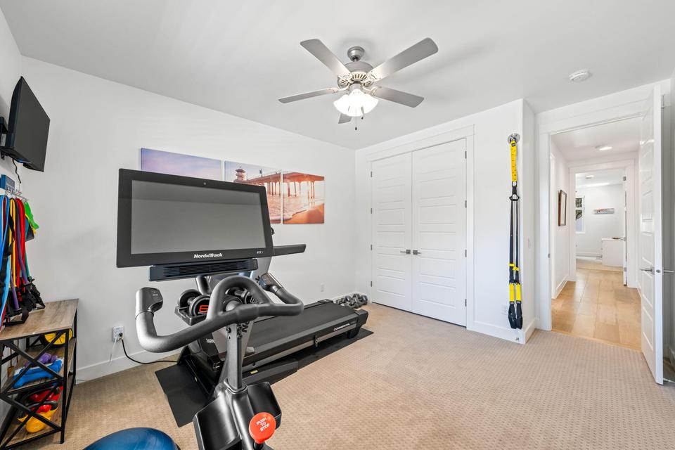 Exercise room with light carpet and a ceiling fan