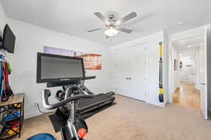 Exercise room with light carpet and a ceiling fan