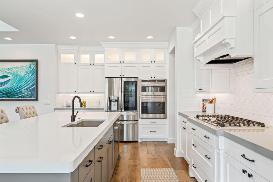 Kitchen featuring stainless steel appliances, light wood-type flooring, two tone cabinetry, recessed lighting, and light stone counters