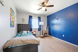 Bedroom featuring light wood-style floors, a ceiling fan, and a textured ceiling