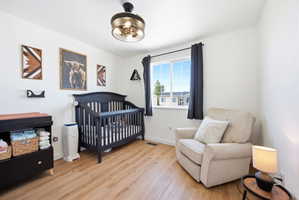 Bedroom with a nursery area and light wood-style floors