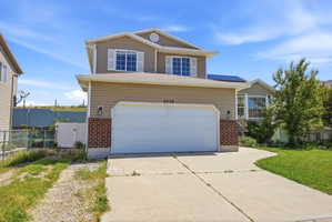 Traditional home featuring brick siding, concrete driveway, roof mounted solar panels, and a gate