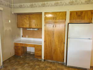 Kitchen with freestanding refrigerator, light countertops, wood finish cabinetry, and built in study area
