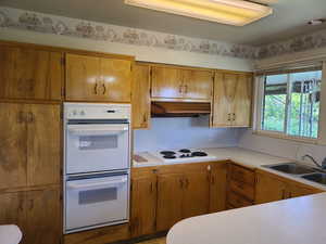 Kitchen featuring light countertops, white appliances, and wood finish cabinetry