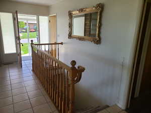 Hallway with an upstairs landing and light tile patterned floors