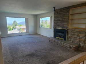 Unfurnished living room with a fireplace, built in shelves, plenty of natural light, and carpet