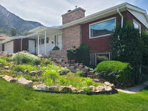 View of front of home with an attached garage, stone siding, a porch, a chimney, and brick siding