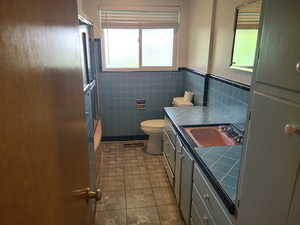Full bathroom with vanity, tile walls, wainscoting, and washtub / shower combination
