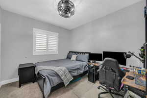 Carpeted bedroom featuring a desk and baseboards