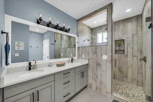 Full bath featuring double vanity and a stall shower