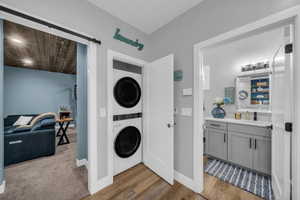 Laundry room with stacked washer / dryer and light wood-type flooring