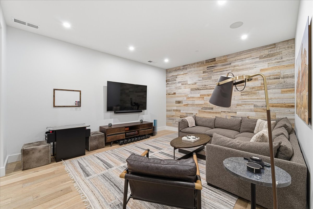 Living room featuring an accent wall, wood walls, recessed lighting, and light wood-style flooring