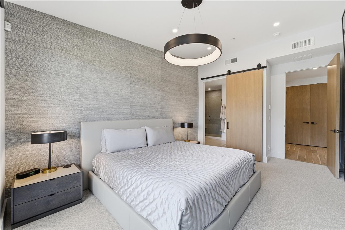 Bedroom with a barn door, light carpet, and recessed lighting