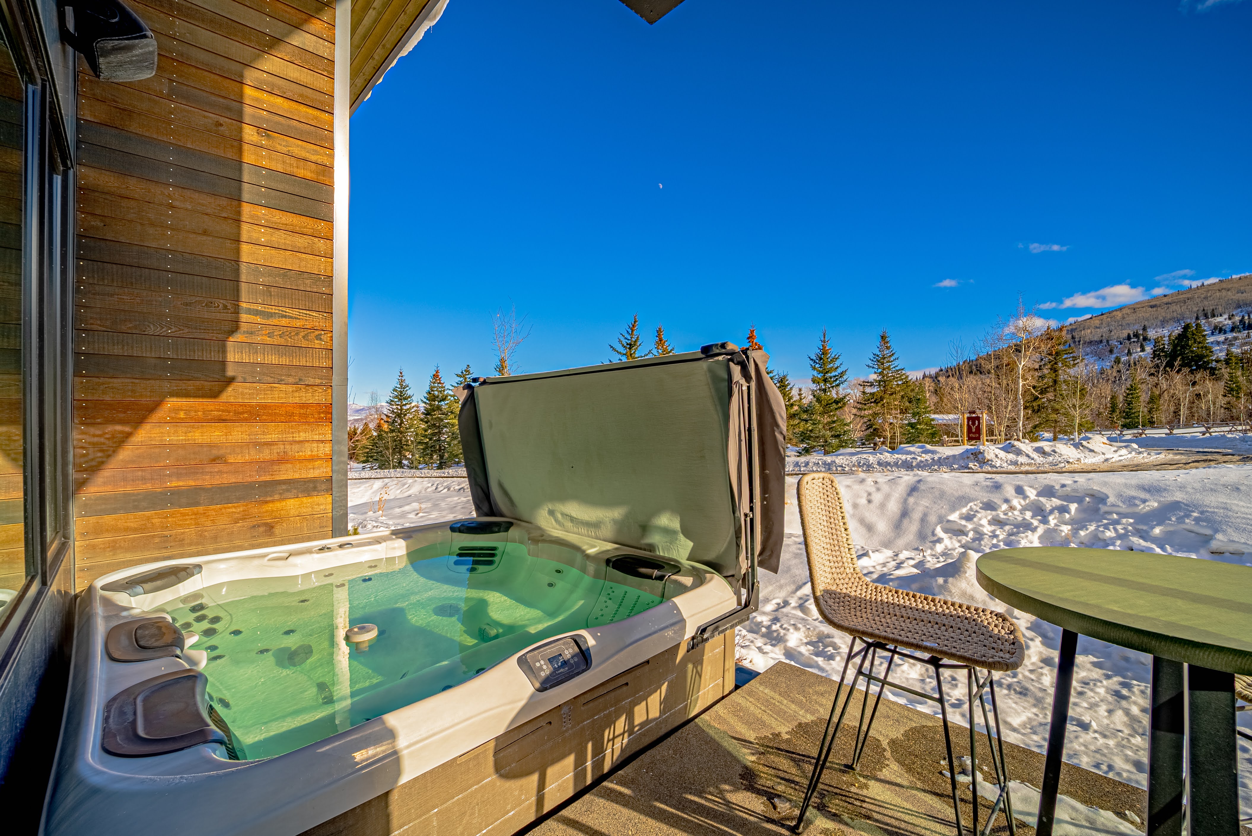Snow covered deck featuring a hot tub and a mountain view