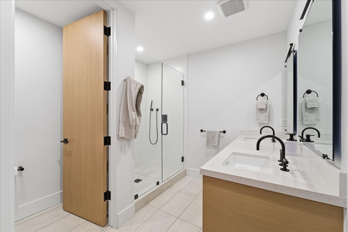 Full bathroom with a shower stall, double vanity, recessed lighting, and light tile patterned floors
