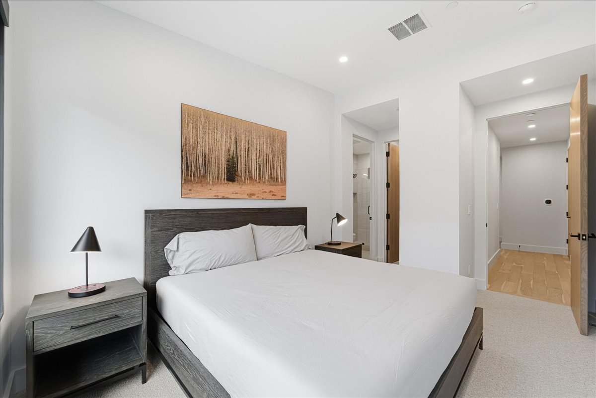 Bedroom with ensuite bathroom, light carpet, and recessed lighting
