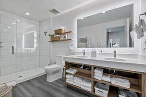 Bathroom with double vanity, a stall shower, dark wood-style flooring, and recessed lighting