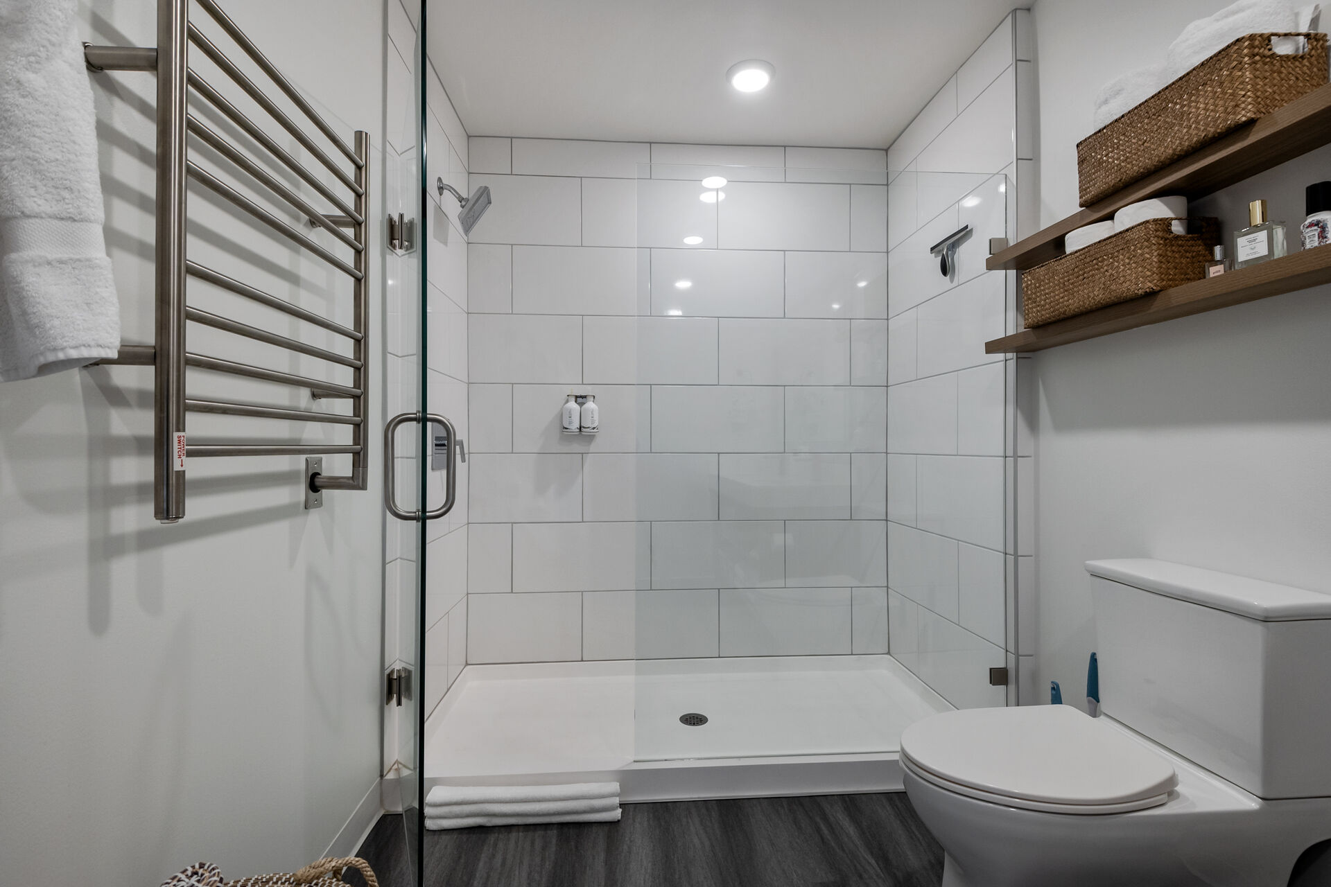 Bathroom featuring a towel warming rack, radiator heating unit, a shower stall, and dark wood-style floors