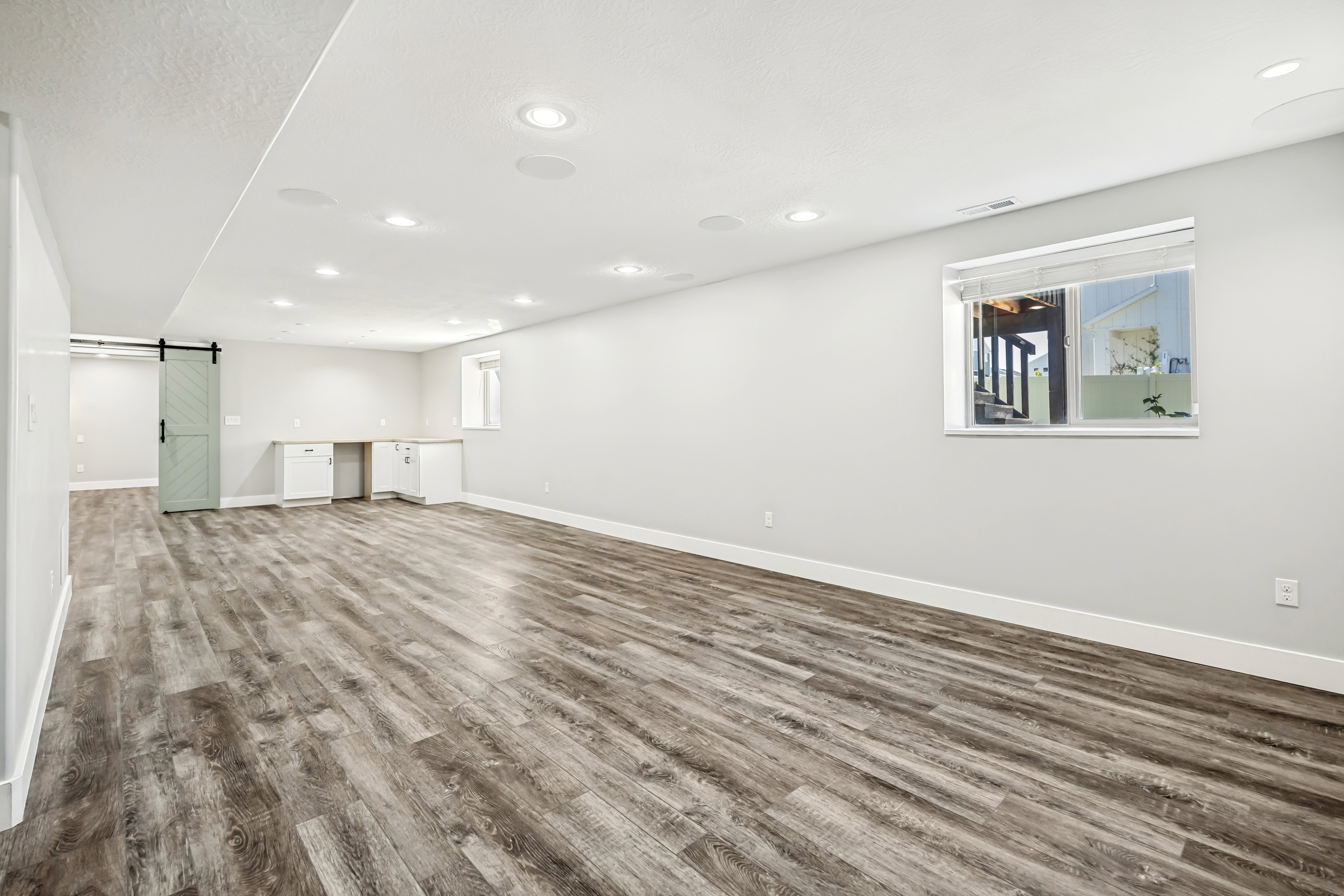 Unfurnished living room with dark wood finished floors, a barn door, built in study area, and recessed lighting