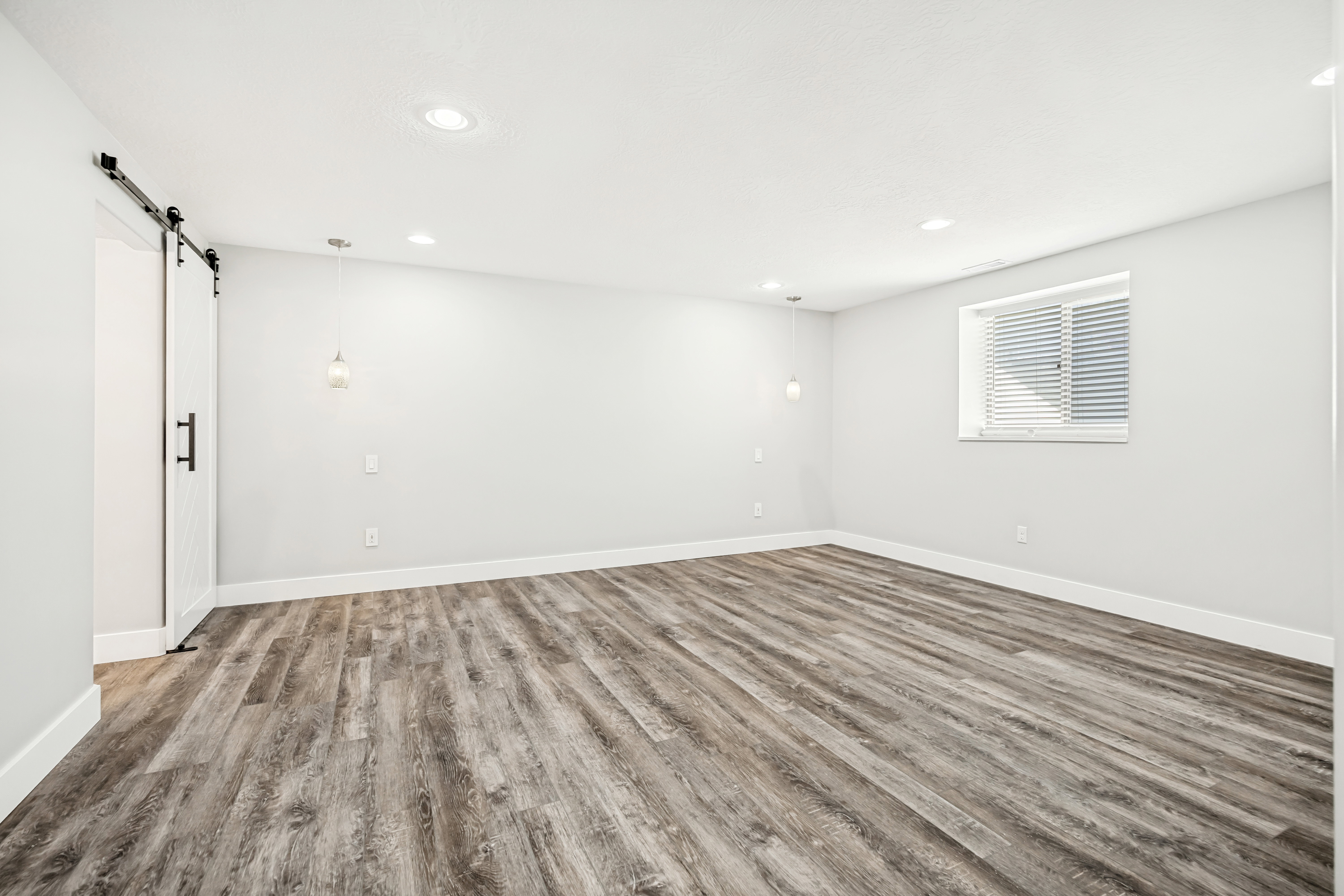 Unfurnished room featuring a barn door, light wood finished floors, and recessed lighting