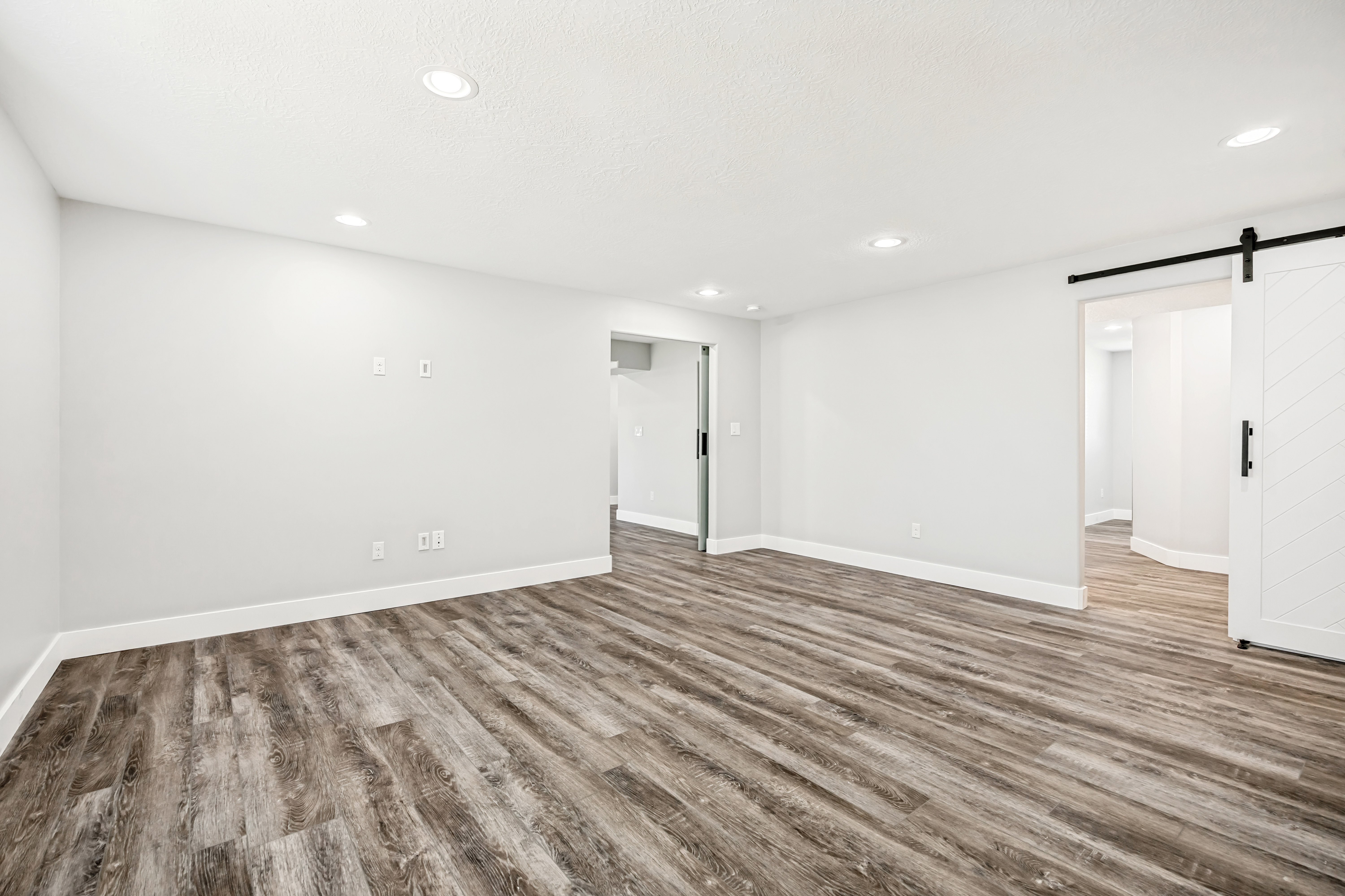 Unfurnished room with a barn door, wood finished floors, and recessed lighting