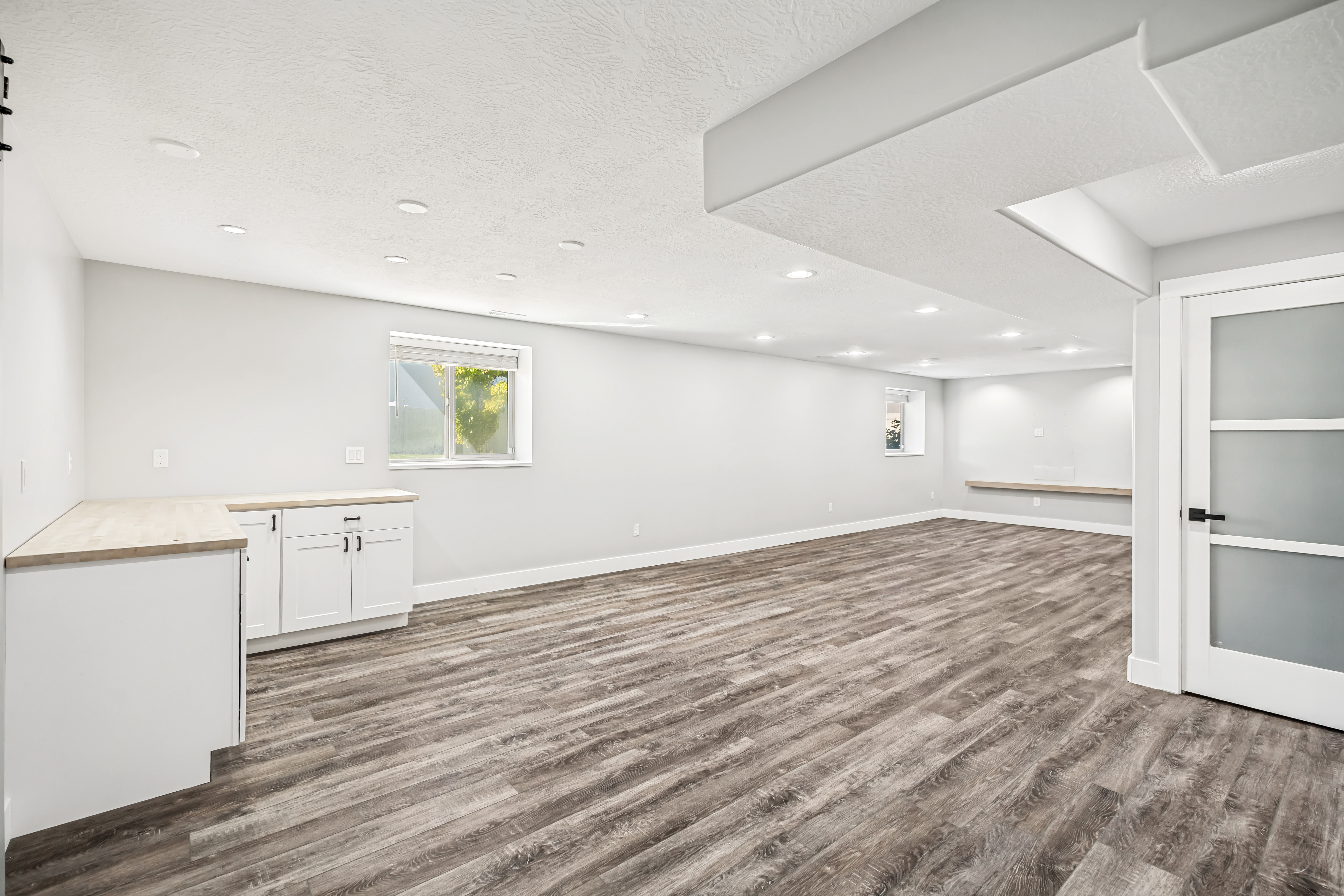 Below grade area featuring dark wood-type flooring, a textured ceiling, and recessed lighting