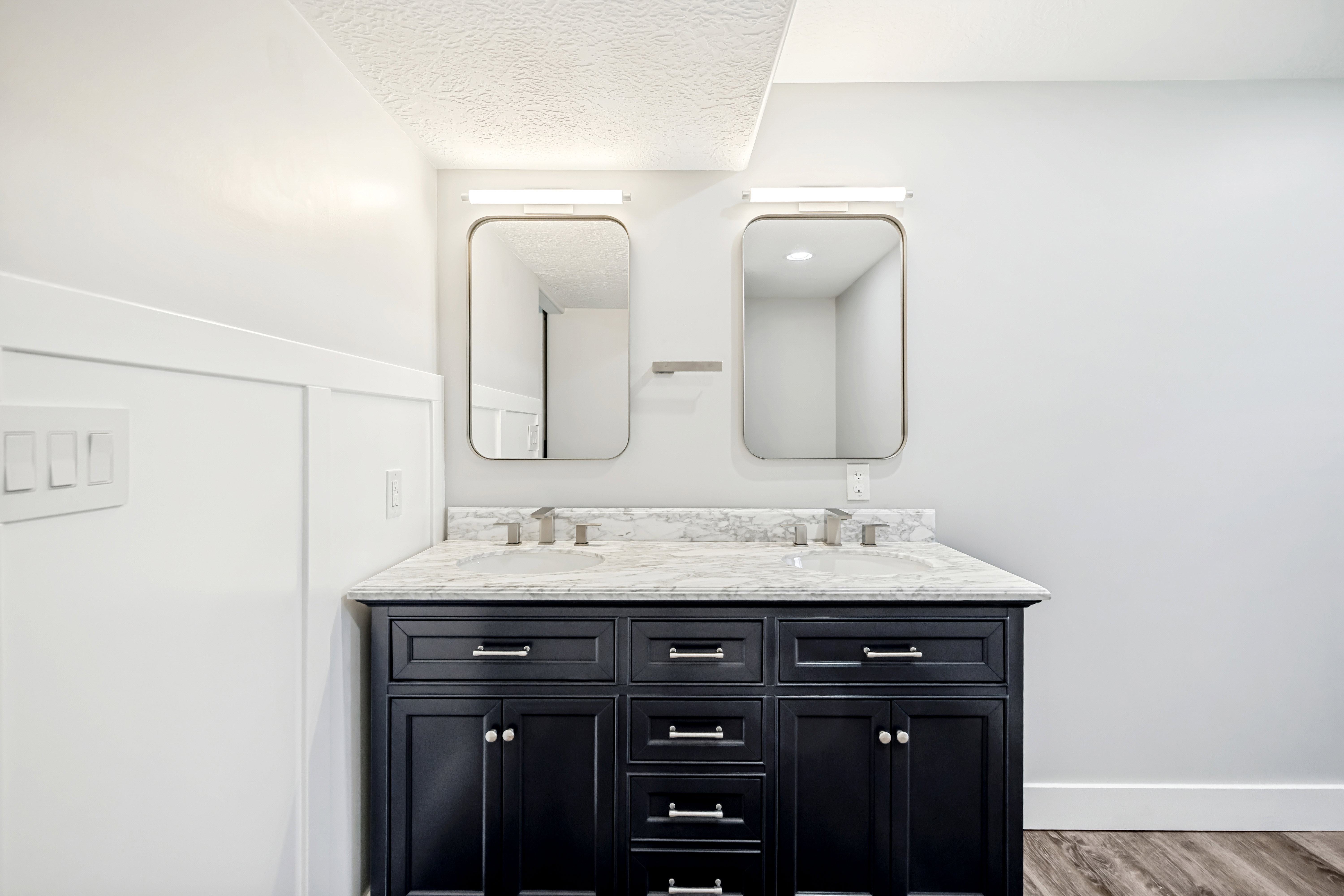 Bathroom featuring double vanity, wood finished floors, and a textured ceiling