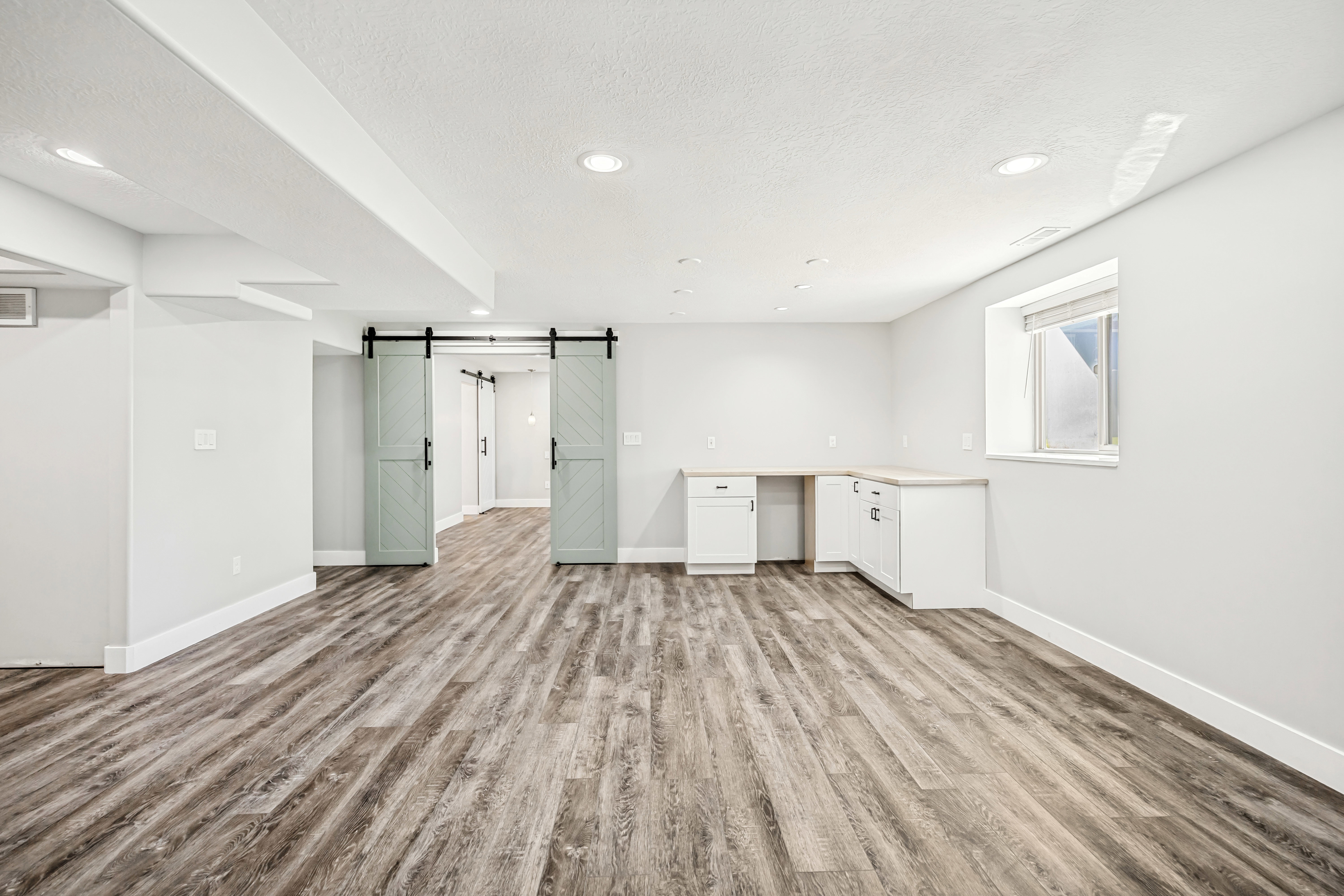 Interior space featuring a barn door, light wood finished floors, recessed lighting, a textured ceiling, and built in desk