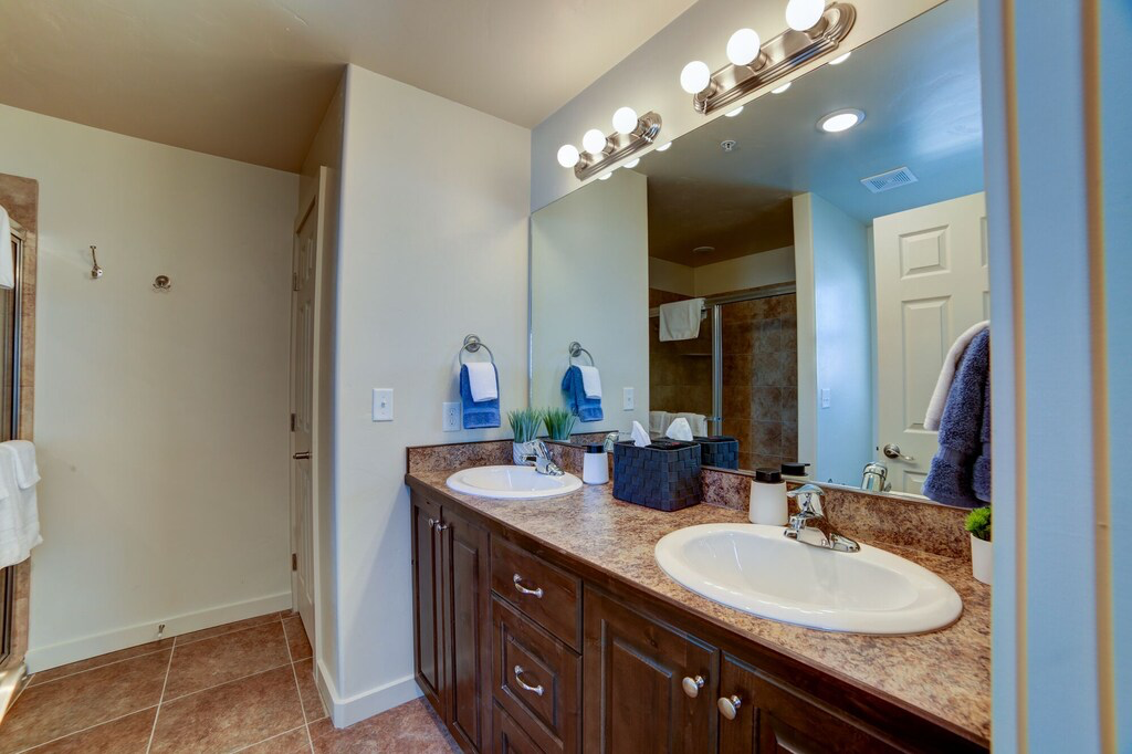 Full bath featuring double vanity, a stall shower, and light tile patterned flooring
