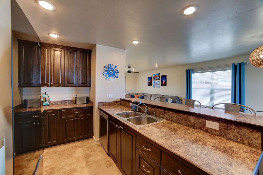 Kitchen with dark wood finish cabinets, ceiling fan, recessed lighting, a peninsula, and stainless steel dishwasher