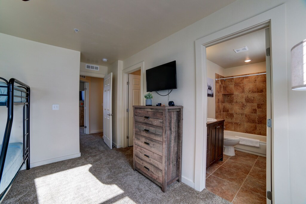 Bedroom with light colored carpet and connected bathroom
