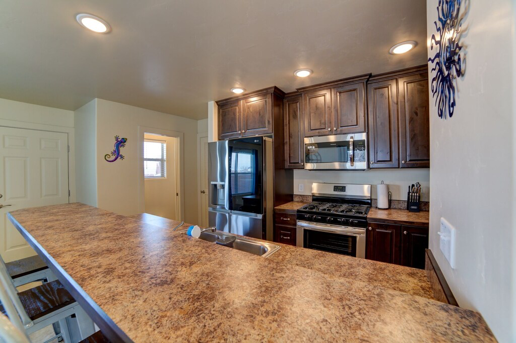 Kitchen with stainless steel appliances, dark wood finish cabinets, a breakfast bar area, and recessed lighting