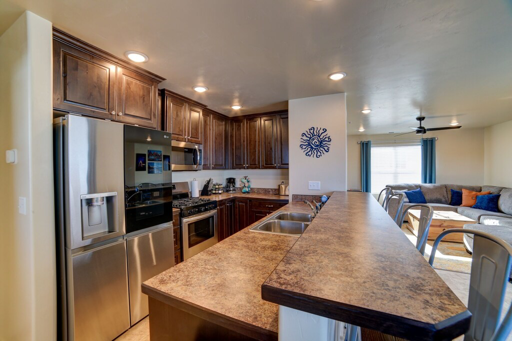 Kitchen with a kitchen bar, stainless steel appliances, a peninsula, dark wood finish cabinetry, and open floor plan