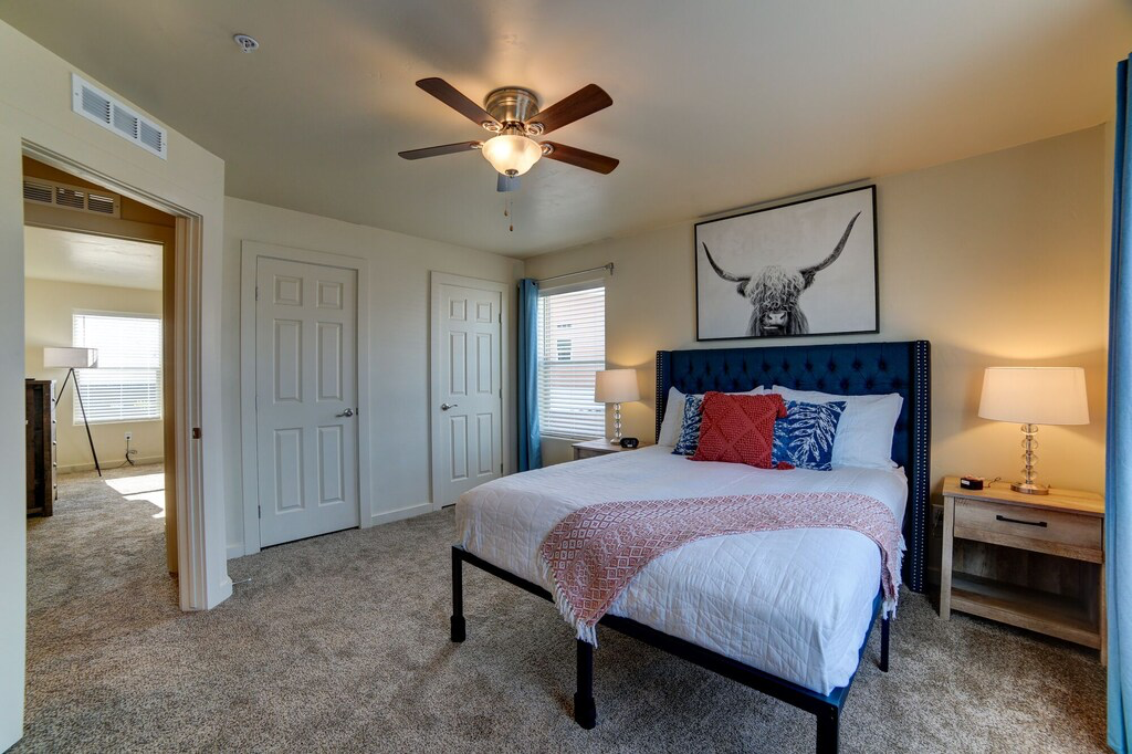 Bedroom with two closets, carpet floors, and a ceiling fan
