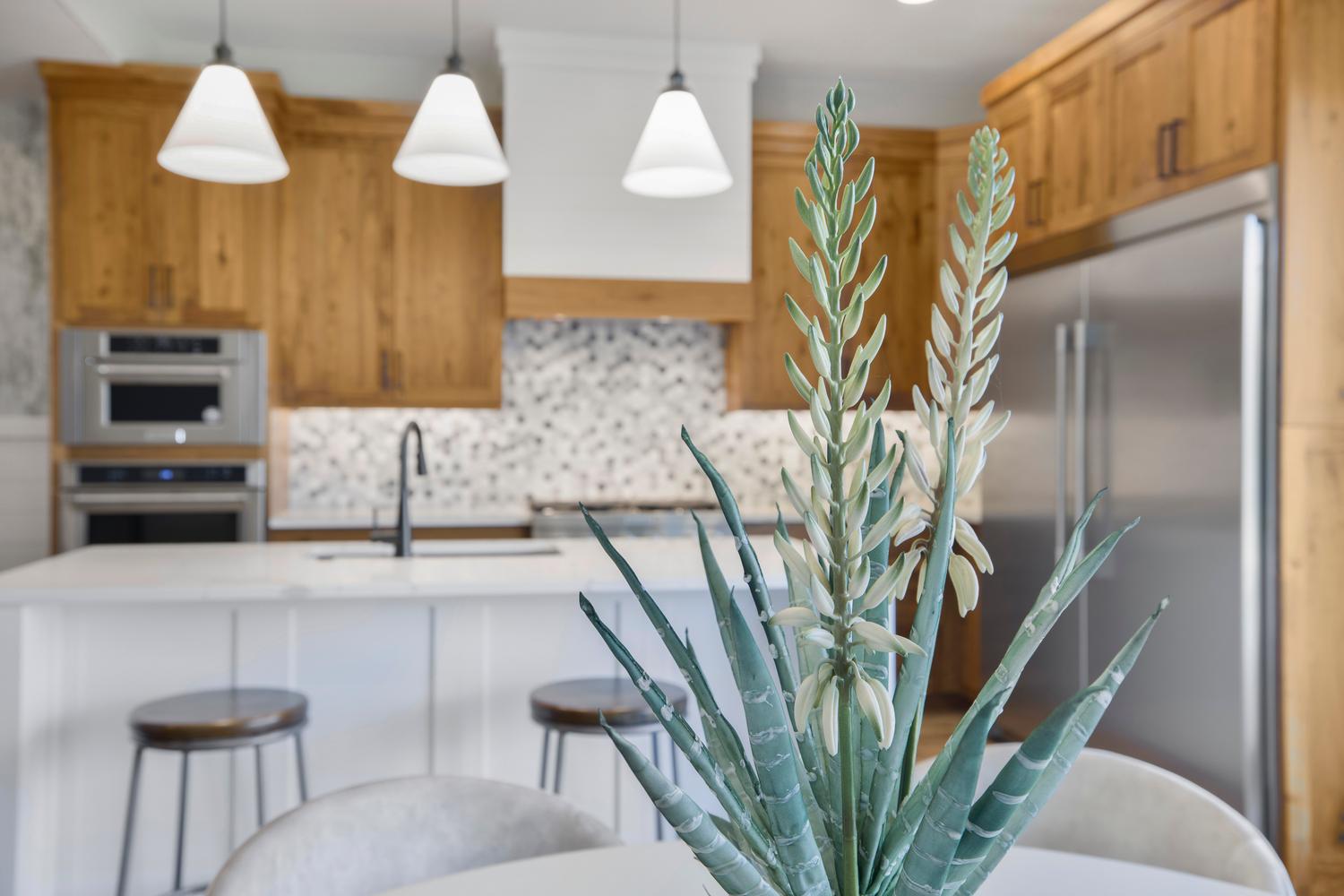 Kitchen with a kitchen breakfast bar, stainless steel refrigerator, an island with sink, pendant lighting, and double oven