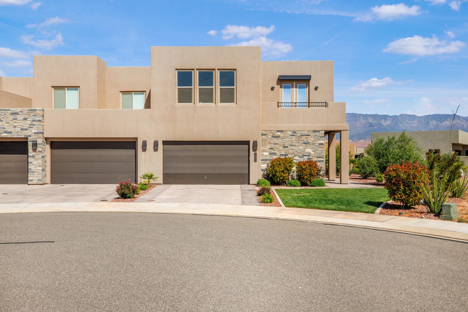 View of front of house with concrete driveway, stucco siding, stone siding, and an attached garage