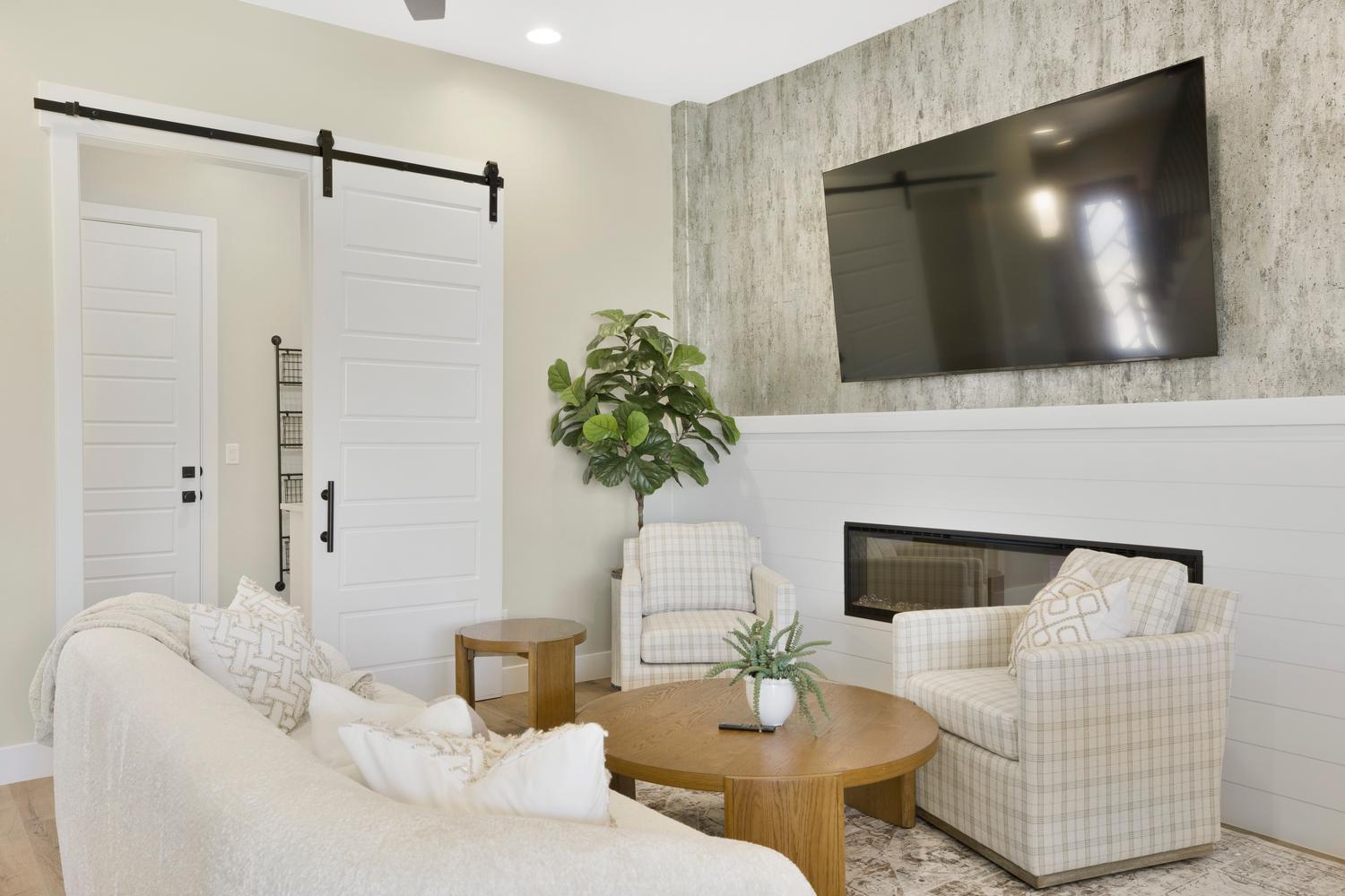 Living area with a glass covered fireplace, a barn door, and an accent wall
