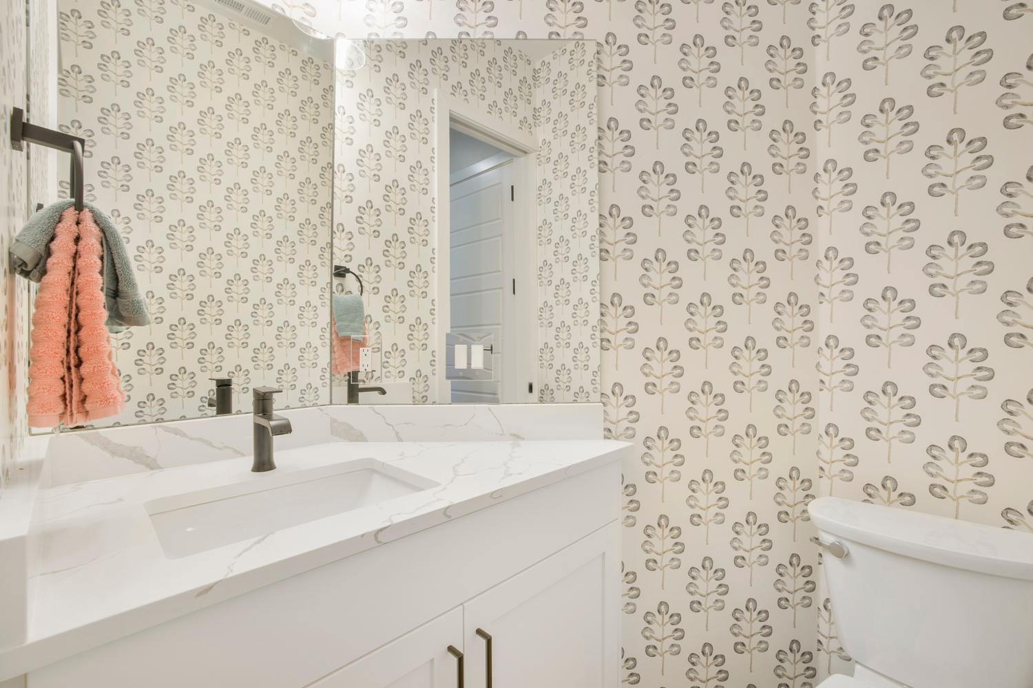 Half bath featuring vanity and wallpapered walls