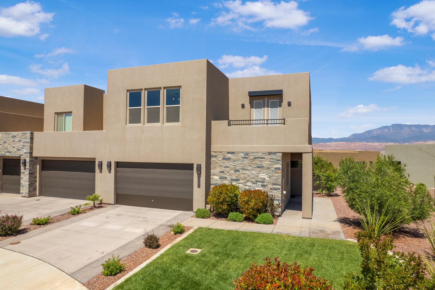 View of front of house featuring driveway, stucco siding, a mountain view, stone siding, and a garage