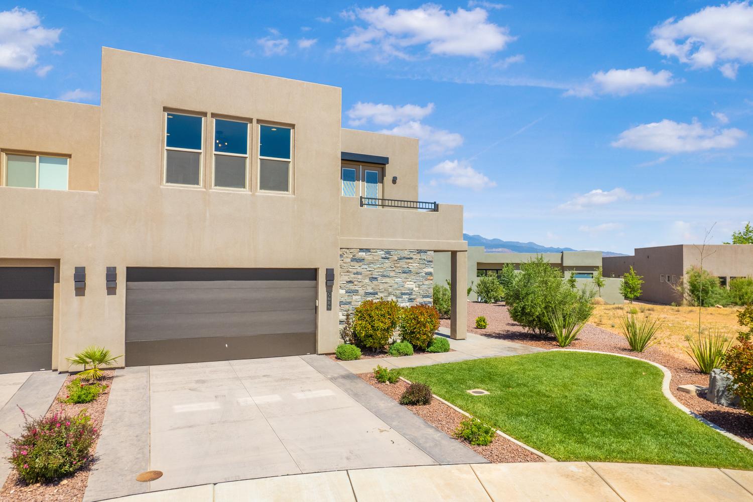 View of front of home featuring a garage, stucco siding, concrete driveway, and a front lawn