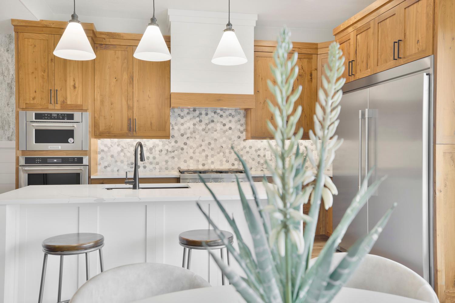 Kitchen featuring stainless steel appliances, a breakfast bar area, light stone counters, decorative light fixtures, and an island with sink